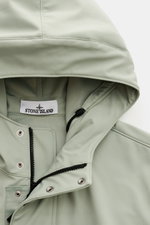 Close-up front view of Stone Island Blouson 'Light Soft Shell-R' salbei jacket hood, zipper, snaps, and mesh lining, showcasing soft shell fabric.