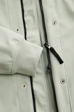 Close-up front view of Stone Island Blouson 'Light Soft Shell-R' salbei, showing sage green soft shell fabric, ribbed elastic cuff, two-way black zipper, snap button wind flap, and mesh lining. Stil trifft Funktion: Die Soft Shell Jacke von STONE ISLAND ü