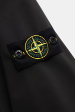 Close-up of the compass badge on the upper sleeve of the Stone Island Jacket 'Light Soft Shell-R' black, photographed from a side angle. Style meets function: This soft shell jacket by STONE ISLAND has a sporty design in a three-layer functional material 