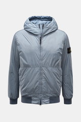 Front view of the Stone Island Blouson 'Garment Dyed Crinkle Reps NY' rauchblau, a sporty lightweight microfiber jacket with a crinkled resin finish, padded hood, elastic cuffs and hem, two-way zipper, zipper pockets, and signature compass badge on the up