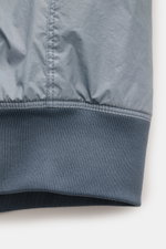 Close-up view of the ribbed elastic hem on the Stone Island Blouson 'Garment Dyed Crinkle Reps NY' rauchblau, showcasing the lightweight microfiber fabric with crinkle resin coating, highlighting the jacket’s wind- and water-resistant qualities and detail
