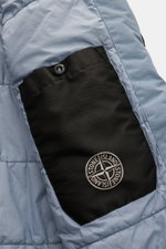 Close-up side view of the Stone Island Blouson 'Garment Dyed Crinkle Reps NY' rauchblau showing the black inner pocket with button and the compass badge on light blue microfiber fabric. Funktion trifft Style: Der sportive Blouson von STONE ISLAND besteht 