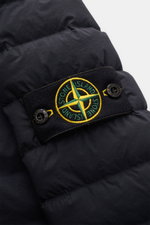 Close-up view of the Stone Island Daunenjacke 'Seamless Tunnel Nylon Down-TC' dark navy, showing the iconic compass badge on the dark navy, water-repellent microfiber fabric with lightweight down filling. Die Jacke 'Seamless Tunnel Nylon Down-TC' von STON