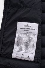 Close-up inside view of Stone Island Daunenjacke 'Seamless Tunnel Nylon Down-TC' dark navy label showing fabric details and care instructions.