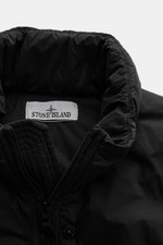 Close-up front view of the Stone Island Daunenjacke 'Seamless Tunnel Nylon Down-TC' schwarz, highlighting the high collar, zipper, and Stone Island label, made with high-quality microfiber, lightweight responsible down filling, slim fit, water-repellent, 