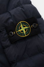 Close-up of the Stone Island Daunenjacke 'Seamless Tunnel Nylon Down-TC' dark navy showing the black patch with yellow and green compass badge on the sleeve. The jacket is made from high-quality microfiber with a smooth touch, lightweight duck down fillin