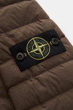 Close-up shot of the Stone Island Daunenjacke 'Seamless Tunnel Nylon Down-TC' braun showing the black compass badge with yellow and green embroidery on brown quilted fabric.

Description: <p>Die Jacke 'Seamless Tunnel Nylon Down-TC' von STONE ISLAND überz