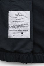 Close-up from above of the Stone Island Blouson 'Stretch Cotton Twill-TC' navy label sewn inside the elastic hem, showing fabric details and care instructions. Sportives Frühlings-Essential: Mit seinem leichten Baumwollmaterial wird der STONE ISLAND Blous
