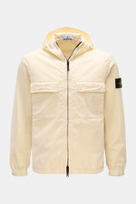 Front view of the Stone Island Blouson 'Stretch Cotton Twill-TC' creme, a slim fit spring jacket in elastic, soft cotton with garment dyed fabric, featuring a robust two-way zipper, hood with drawstring, chest patch pockets, side seam front pockets, and e