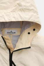Close-up, front-top view of Stone Island Jacket 'Membrana' cream, showing the drawstring hood, two-way zip, and label inside. Function meets style: The triple-layer functional fabric of this STONE ISLAND jacket is laminated with a breathable, water repell