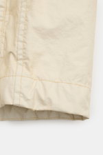 Close-up of the hem of the Stone Island Jacket 'Membrana' cream, showing lightweight, wind and water repellent fabric from a front-side angle.