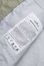 Nahaufnahme des Innenetiketts der Stone Island Jacke 'Membrana' salbei, mit Details zu atmungsaktivem, wasserabweisendem Funktionsgewebe.