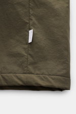 Nahaufnahme des Saums mit Logo-Weblabel des 04651/ A trip in a bag Parka 'The Coat' oliv aus hochwertiger Microfaser.