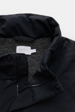 Close-up front top view of the 04651/ A trip in a bag Jacket dark navy showing high-quality microfibre, smooth feel, lightweight padding, wind and water repellent fabric, regular fit, zip, concealed hood in collar, raglan sleeves, hip pockets with flap, s