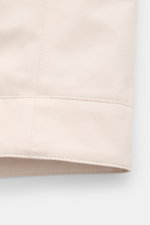 Close-up of the hem stitching of the Fay Blouson beige, photographed from a side angle, showcasing smooth cotton, silk, and cashmere blend fabric with a slim fit and elasticated cuffs.