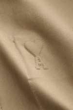 Nahaufnahme des taupefarbenen Ami Paris Blouson mit feinem Baumwollstoff und dezentem Logo-Stitching in Herzform, Detailansicht.