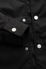 Nahaufnahme der Ami Paris Jacke schwarz von vorne mit Fokus auf Druckknopfleiste und Ärmelabschluss mit Knopf, glatte Microfaser.