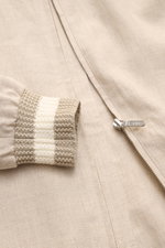 Ché Blouson 'Benito' beige meliert aus reinem Leinen, Slim Fit, halb gefüttert, mit Umlegekragen, robustem Reißverschluss, paspelierten Fronttaschen, elastischen Saum- und Ärmelbündchen, zwei Innentaschen; Detailaufnahme von Ärmelbündchen und Front.