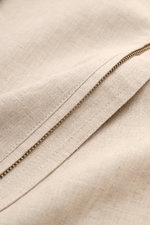 Nahaufnahme des robusten Reißverschlusses und der fein gewebten Leinenstruktur des Ché Blouson 'Benito' beige meliert.