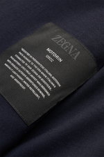 Close-up of the Zegna Jacket 'Motorin' navy label on the soft, high-quality microfibre fabric, photographed from above showing detailed text. <section class="text-token-text-primary w-full focus:outline-none [--shadow-height:45px] has-data-writing-block:p