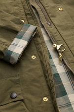 Barbour Wachsjacke 'Icons Border Casual' oliv in Nahaufnahme von oben, gewachste Baumwolle, Tartan-Futter, Reißverschluss, Druckknöpfe, Cord-Kragen.