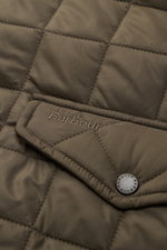 Nahaufnahme der olivfarbenen Barbour Steppjacke 'Chelsea Sportsquilt' mit gesteppter Microfaser, tonalem Stitching und Pattentasche.
