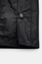 Nahaufnahme der Barbour Wachsjacke 'Bedale' dark navy, Frontbereich mit gewachster Baumwolle, Druckknopf mit Logo und robustem Materialgriff.