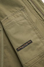 Close-up from above of the olive Barbour Field jacket 'Sanderling' showing lightweight fabric, sleeve pocket with Barbour Tartan label, and detailed stitching. Lightweight, functional and classic style: The versatile field jacket 'Sanderling' by BARBOUR i