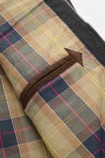 Innenansicht des Barbour Parka 'Icons Border' dark navy mit Tartan-Innenfutter, Innentasche und Reißverschluss im Detail, seitliche Perspektive.