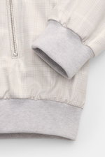 Close-up front view of the Moorer Blouson 'Sorano' light grey/beige/cream checked, showing elastic hem, sleeve cuff, two-way zip, and classic checked pattern. Made of pure cotton with soft feel, slim fit, classic blouson collar, zip front pockets, soft je
