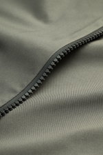 Nahaufnahme der graugrünen Microfaser der UBR Jacke 'Nano' mit glattem Griff und robustem Zwei-Wege-Reißverschluss, wind- und wasserabweisend.