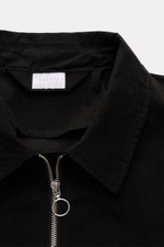 Nahaufnahme des schwarzen 04651/ A trip in a bag Blouson 'Peached Cotton' mit Umlegekragen, robustem Reißverschluss und weichem Material, von oben fotografiert.