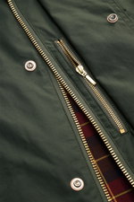 Close-up image of the dark green Manifattura Ceccarelli Waxed jacket 'Raincaban' showing the gold two-way zipper and snap buttons from a top-down perspective, revealing the iconic tartan lining. Authentic outerwear with vintage character: The Italian-made