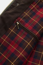 Close-up interior view of the Manifattura Ceccarelli Waxed jacket 'Raincaban' dark green, showing its iconic red, navy, and brown tartan lining with a zippered inside pocket and dark brown trim. Authentic outerwear with vintage character: The Italian-made