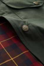 Nahaufnahme der dunkelgrünen Manifattura Ceccarelli Wachsjacke 'Heavy Shirt' mit gewachster Baumwolle, Tartan-Futter und Druckknopf.