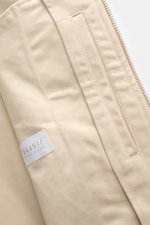 Nahaufnahme des beigen 04651/ A trip in a bag Blouson 'Griffin' mit Baumwollstoff, Reißverschluss, Innentasche und Slim Fit, frontal fotografiert.