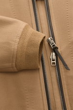 Nahaufnahme des Tom Ford Blouson hellbraun von schräg oben, mit Fokus auf zwei-Wege-Reißverschluss, elastischem Rippbündchen und feiner Schurwoll-Seidenmischung.