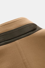 Nahaufnahme des hellbraunen Tom Ford Blousons aus Schurwoll-Seidenmischung, Fokus auf Stehkragen mit Leder-Riegel, schräger Naht, Detail von oben fotografiert.