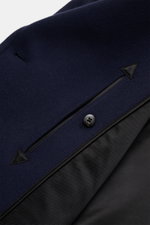 Nahaufnahme der Tom Ford Cabanjacke navy aus reiner Wolle, weicher Griff, Slim Fit, mit breitem Reverskragen, Lederdetails, paspelierten Taschen und glattem Futter, von schräg oben fotografiert.
