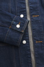 Nahaufnahme der A.P.C. Jeansjacke navy aus reiner Baumwolle in griffiger Qualität, Slim Fit mit Umlegekragen, fünf Knöpfen, vier Fronttaschen und Ärmelabschlüssen mit Knopf. Perspektive frontal auf Knopfleiste und Ärmel.
