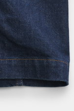Nahaufnahme des Ärmels der A.P.C. Jeansjacke navy, fotografiert aus seitlicher Perspektive, Denim aus reiner Baumwolle, griffig, Slim Fit, fünf Knöpfe, Umlegekragen, vier Fronttaschen, Ärmel mit Knopf.