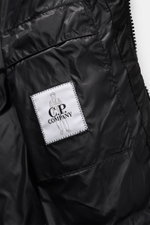Nahaufnahme der Innenansicht der C.P. Company Daunenjacke 'DD-Shell' schwarz mit gestepptem Mikrofasermaterial und Logo-Patch, glatter Griff.