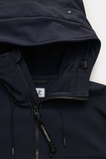 Nahaufnahme der Kapuze und des robusten Zwei-Wege-Reißverschlusses der C.P. Company Softshell-Jacke 'C.P. Shell-R Goggle Jacket' navy aus recycelter Microfaser, fotografiert von oben.