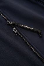 Nahaufnahme der C.P. Company Softshell-Jacke 'C.P. Shell-R Goggle Jacket' navy in futuristischer Ausführung, Fokus auf Reißverschluss mit Label, recycelte Microfaser, wind- und wasserabweisend, Slim Fit.