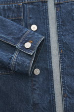 Stone Island Jeansjacke 'Indigo Denim-Rinsed' dunkelblau, Detailaufnahme von Ärmel und verdeckter Knopfleiste, Baumwoll-Denim, slim fit, Kompass-Badge sichtbar.