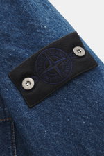 Stone Island Jeansjacke 'Indigo Denim-Rinsed' dunkelblau, Nahaufnahme des schwarzen Kompass-Badges mit Knöpfen auf indigogefärbtem Denim aus Baumwolle.