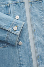 Close-up front view of Stone Island Jeansjacke 'Indigo Denim-Rinsed' dunkelblau showing slim fit denim fabric, concealed button placket, buttoned cuff, patch pockets, and compass badge on sleeve.

<p>Lässige Denim-Looks: Die aus indigogefärbtem Baumwoll