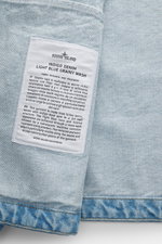 Stone Island Jeansjacke 'Indigo Denim-Rinsed' dunkelblau close-up from above showing fabric texture and label with product details.  
<p>Lässige Denim-Looks: Die aus indigogefärbtem Baumwollgarn gefertigte Jeansjacke der STONE ISLAND 'Denim' Capsule Coll
