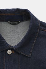 Close-up front view of the Stone Island Denim jacket 'Indigo Denim-Rinsed' dark blue showing the turn-down collar, concealed button placket, and signature button with orange stitching on pure cotton denim fabric. For casual denim looks: This denim jacket 