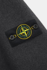 Close-up of the Stone Island Jacke 'No Seasons Garment Dyed Crinkle Reps NY' graugrün showing the embroidered compass badge on the upper sleeve, captured from a top-down angle.

Description: <p>Eine Jacke, sechs Materialien: Das ist die Kollektion 'No S
